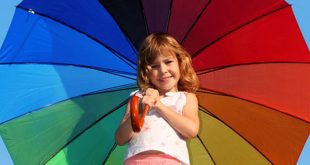 Kleines Mädchen mit einem aufgespannten Regenbogenschirm