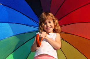 Kleines Mädchen mit einem aufgespannten Regenbogenschirm